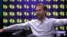 a man in a white shirt is sitting in front of a screen that says ' fox news ' on it