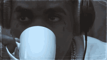 a man with a tear in his eye drinking from a white cup