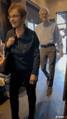 a man and a woman are walking down a hallway and the woman is smiling .