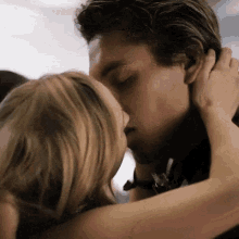 a man and a woman are kissing in a close up of their faces .
