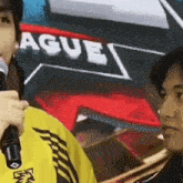 a man is holding a microphone in front of a sign that says league