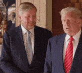 two men in suits and ties are standing next to each other and laughing .