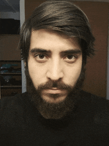 a man with a beard is wearing a black polo shirt