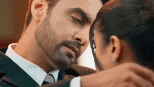 a man in a suit and tie is kissing a woman in a room .