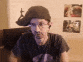 a man wearing a hat , glasses , and headphones is sitting in front of a computer .