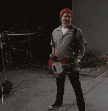 a man wearing a red hat is playing a bass guitar