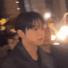 a close up of a man 's face with a blurry background of a city at night .