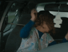 a woman is sitting in the back seat of a car adjusting her seat belt ..