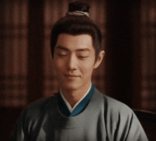 a man with his eyes closed is wearing a gray shirt and blue tie
