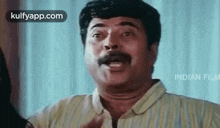 a man with a mustache is making a funny face while talking .