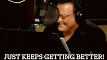 a man wearing headphones is sitting in front of a microphone and says just keeps getting better !
