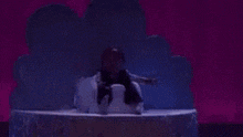 a baby is sitting on top of a snowman on a stage in front of a cloud .