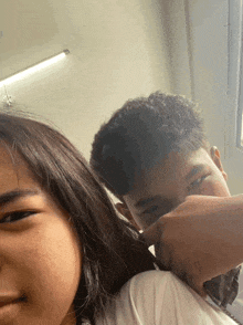 a boy and a girl are posing for a picture and the boy is covering his face with his hand