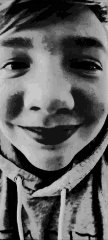 a black and white photo of a young boy wearing a grey hoodie