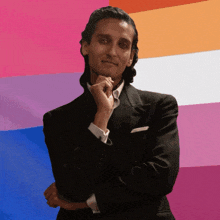 a man in a suit is standing in front of a colorful background