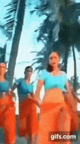 a group of women are dancing in front of palm trees on a beach