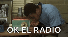 a man is sitting at a table with a radio in front of him and the words ok el radio behind him