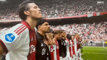 a group of soccer players standing in a line with the number 23 on the scoreboard behind them