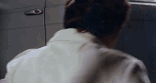 a close up of a person 's back with a gray door in the background