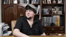 a man is sitting at a desk in front of a bookshelf .