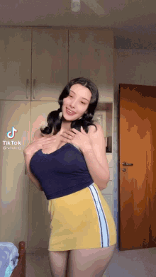 a woman in a blue tank top and yellow skirt is standing in front of a door