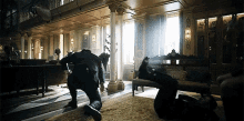 a man is kneeling on the floor in a living room while another man is standing on the floor .