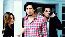a man in a plaid shirt is drinking from a bottle while a woman looks on
