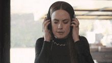 a woman wearing headphones with her eyes closed and a ring on her finger