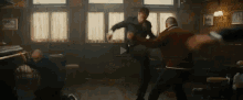 a group of men are fighting in a dark room with a play button in the corner .