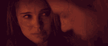 a man and a woman are looking at each other in a dark room