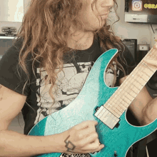 a man with long hair is playing a blue guitar in front of an instagram logo