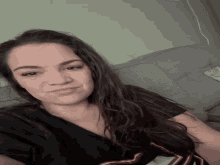 a woman sitting on a couch with a black shirt that has the letter s on it
