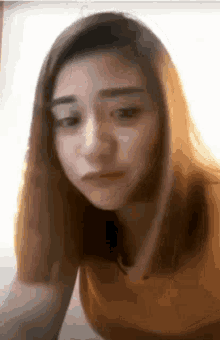 a woman in a yellow shirt is making a funny face and looking at the camera .