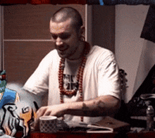a man wearing a white shirt and a necklace that says ' a ' on it