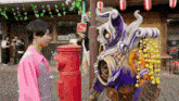 a man in a pink shirt stands next to a purple monster with a sign on his head that says " can "
