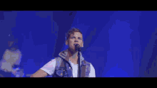 a young man singing into a microphone while playing a guitar