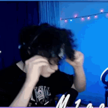 a man wearing headphones is brushing his hair in a room with a blue wall .