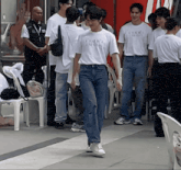 a man wearing a white t-shirt that says ' a few friends ' on it walks through a crowd of people
