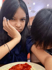 a girl sitting at a table with a plate of spaghetti with ketchup