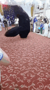 a black bear is dancing on a red carpet in front of a crowd of people .