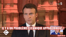 a man in a suit and tie stands in front of a sign that says ' y a un probleme technique apparentement '