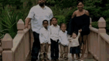 a family standing on a bridge holding hands .