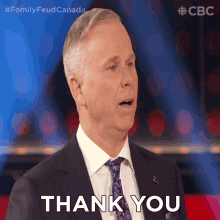 a man in a suit and tie is giving a thank you gesture