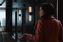 a woman in a red coat is standing in a hallway