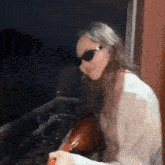 a woman wearing sunglasses is sitting on a balcony holding a balloon .