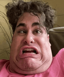 a man in a pink shirt is making a funny face .