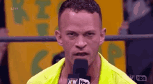 a man is talking into a microphone while wearing a neon yellow jacket .