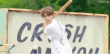 a young boy is swinging a baseball bat in front of a sign that says crush on it .