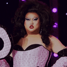 a drag queen is wearing a pink and black corset and gloves