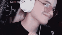 a close up of a person wearing headphones and sunglasses with the word shu written on the wall behind them